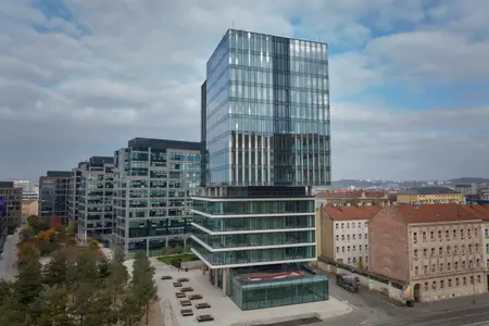 Moderní administrativní budova Vlněna I v Brně s celoprosklenou fasádou, zachycená z nadhledu uprostřed městské zástavby.