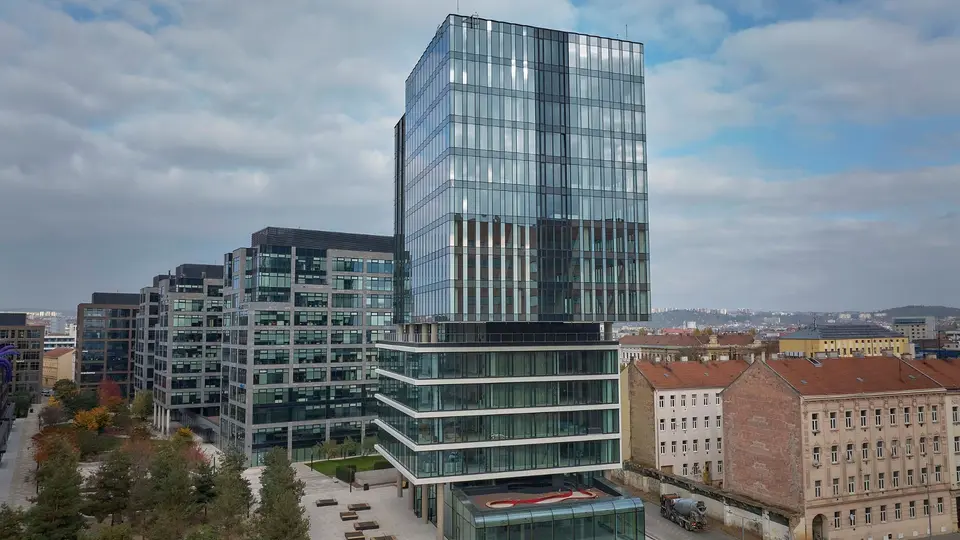 Moderní administrativní budova Vlněna I v Brně s celoprosklenou fasádou, zachycená z nadhledu uprostřed městské zástavby.