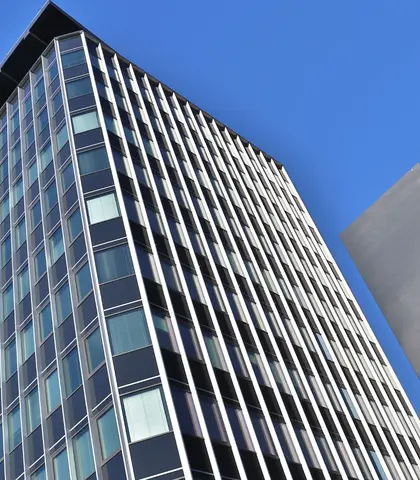 Prosklená moderní budova Černá Perla v Ostravě zachycená z podhledu proti modré obloze, vedle ní štíhlý pylon s nápisem Klinika Černá Perla – Moravian Premium Care.