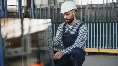 Pracovník v dílně manipuluje s velkoformátovým sklem při výrobě a přípravě zasklení